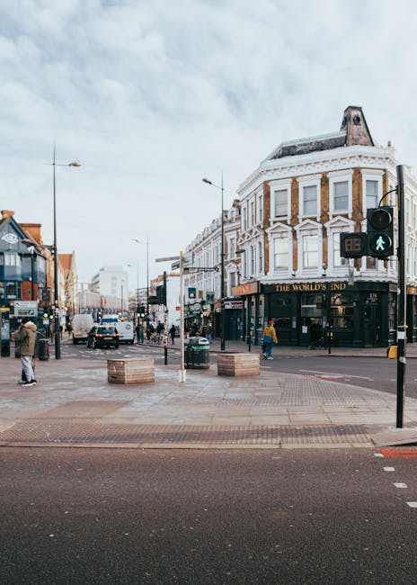 The image depicts a busy urban street scene near Camden Town station during daytime, with a large white building featuring classic architectural details and the sign 'The World's End' on the corner. T